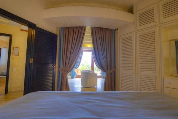 Schlafzimmer im Hotel Ta' Cenc & Spa mit großem Bett und Blick auf einen Garten