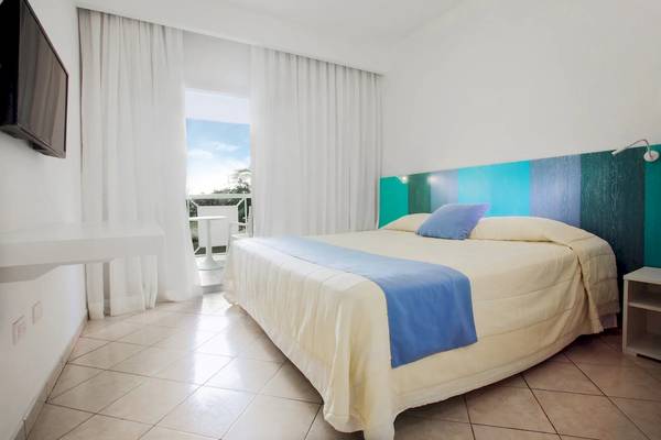 Schlafzimmer im Viva Tangerine by Wyndham Hotel mit Bett, Kissen und Fernseher.