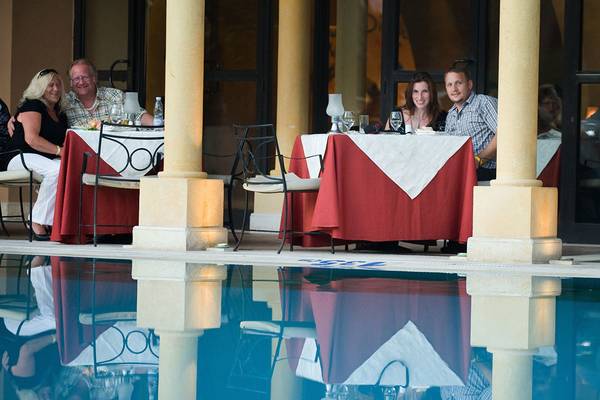 Gäste sitzen am Tisch im Freien neben dem Pool im Makadi Palace Hotel