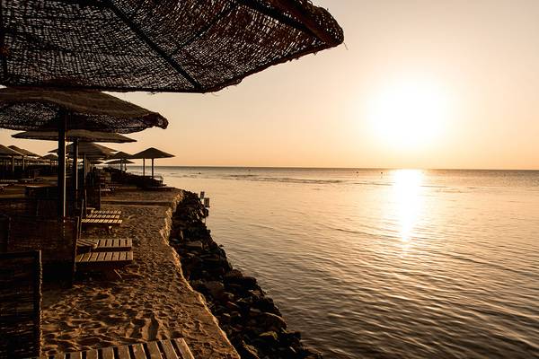 Makadi Palace Hotel: Strandszene mit Sonnenuntergang und Sonnenschirmen am Wasser