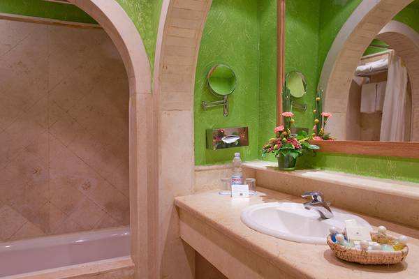 Badezimmer im Makadi Palace Hotel mit grünen Wänden, Badewanne und Waschbecken.