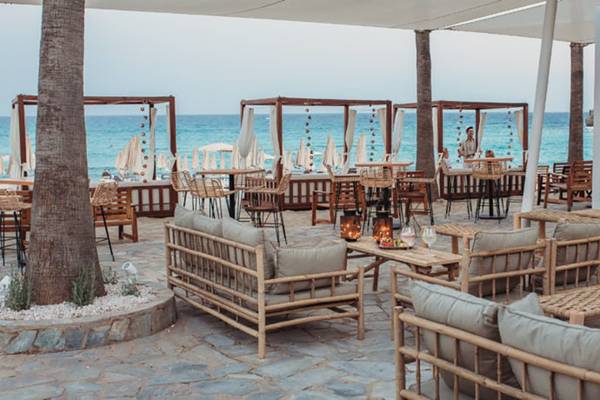 Terrasse des Nissi Beach Resorts mit Blick auf das Meer und moderne Möbel.