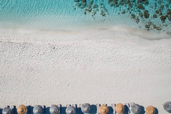 Luftaufnahme des weißen Sandstrands und der Reihe von Sonnenschirmen am Nissi Beach Resort.