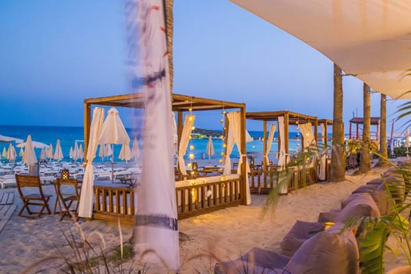 Abendansicht der Nissi Beach Resort Terrasse mit Holzpavillons und Blick auf den Ozean