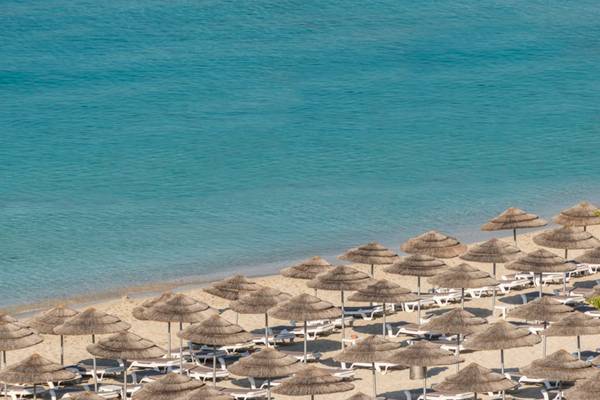 Strand des Nissi Beach Resorts mit vielen Sonnenschirmen und Liegestühlen am Meer