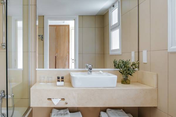Badezimmer im Nissi Beach Resort mit einer Dusche, einem Waschbecken und einem Spiegel.