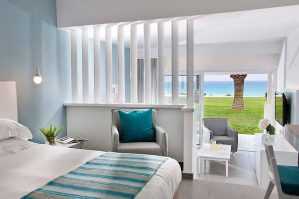 Innenansicht eines Zimmers im Nissi Beach Resort mit Blick auf das Meer und eine Terrasse.