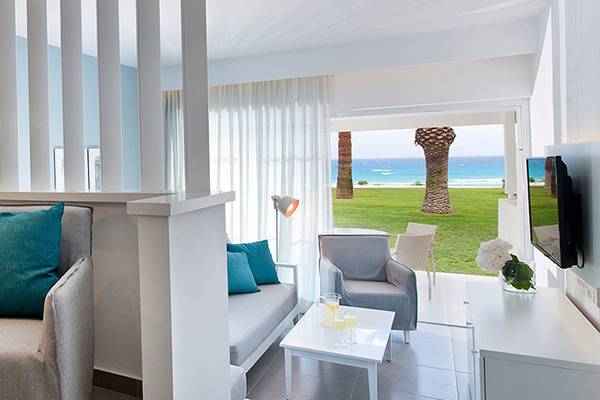 Innenansicht eines Zimmers im Nissi Beach Resort mit Blick auf einen Garten und den Ozean.