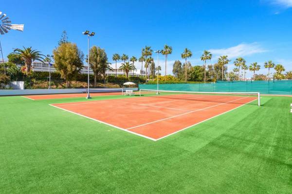 Tennisplatz im Nissi Beach Resort mit grünem Kunstrasen und roten Spielfeldern.