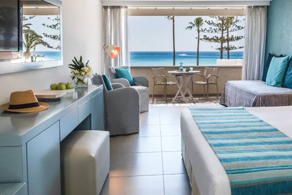 Nissi Beach Resort Zimmer mit Meerblick, blauen Wänden, Terrassenmöbeln und Panoramablick auf den Ozean.