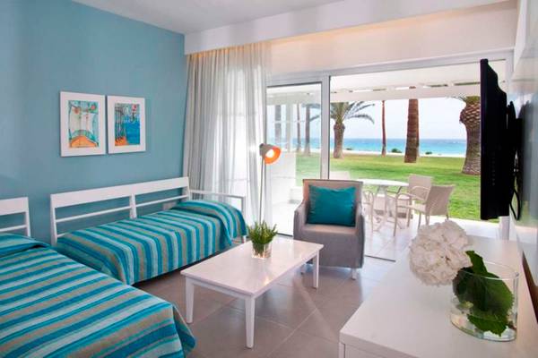 Zimmer im Nissi Beach Resort mit Blick auf das Meer und einen Garten.