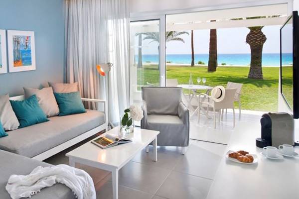 Wohnzimmer des Nissi Beach Resorts mit Blick auf das Meer und einen Garten.