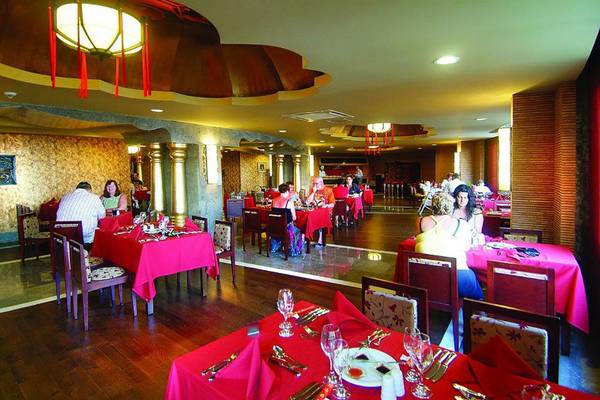 Innenansicht des Restaurants im Royal Dragon Hotel mit Gästen an roten Tischen.