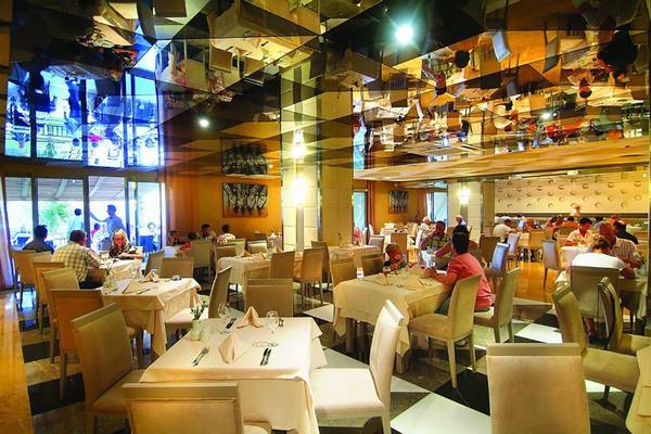 Innenansicht des Restaurants im Royal Dragon Hotel mit spiegelnden Decken und gefüllten Tischen.
