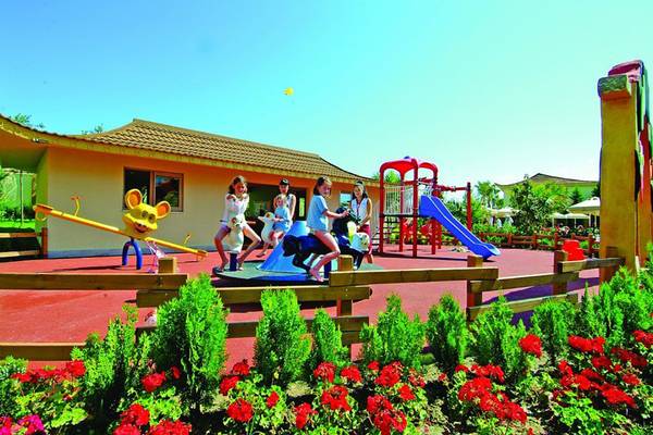 Kinderspielplatz im Royal Dragon Hotel mit Spielgeräten und bunten Blumen.