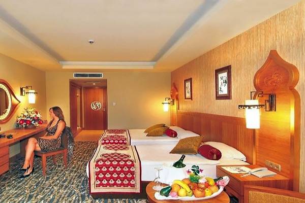 Doppelzimmer im Royal Dragon Hotel mit zwei Betten, Dekor und Möbeln, eine Frau sitzt am Schreibtisch.