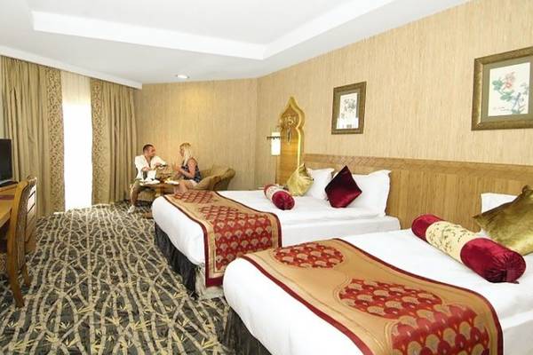Doppelzimmer im Royal Dragon Hotel mit zwei Betten, Fernseher, Tisch und Stühle, Dekor und Gemälde an der Wand.