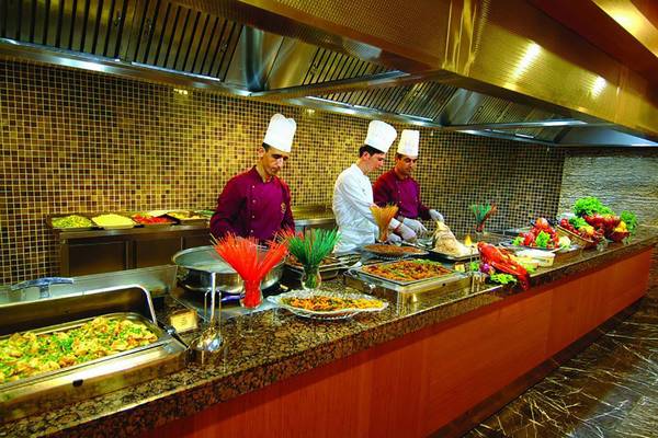 Buffet-Tisch im Royal Dragon Hotel mit Köchen, die Speisen vorbereiten.