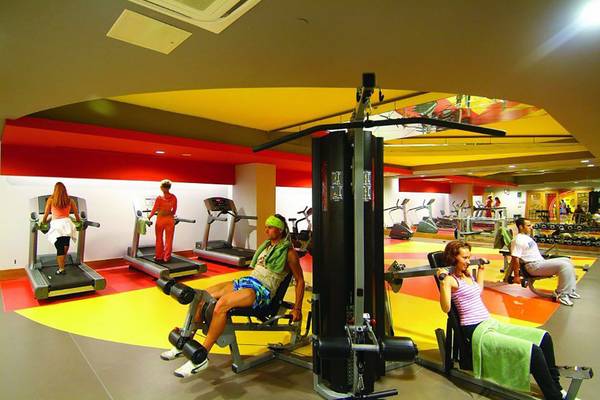 Fitnesscenter im Royal Dragon Hotel mit verschiedenen Trainingsgeräten und aktiven Gästen.