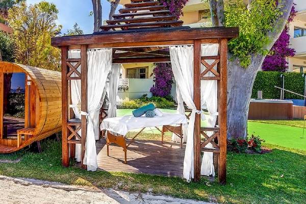 Außenbereich des Viva Golf Adults Only Hotels mit einer Holzsauna und einem Massagetisch unter einer Pergola.