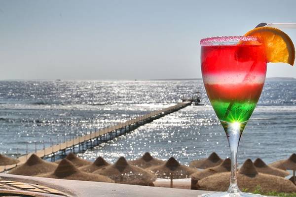 Ein Getränk mit Strohhalm auf einem Tisch am Strand des Charmillion Club Resorts.