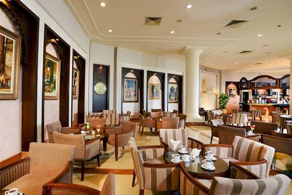Innenbereich des Charmillion Club Resorts Restaurant mit gerahmten Gemälden an der Wand und vielen Tischen und Stühlen.