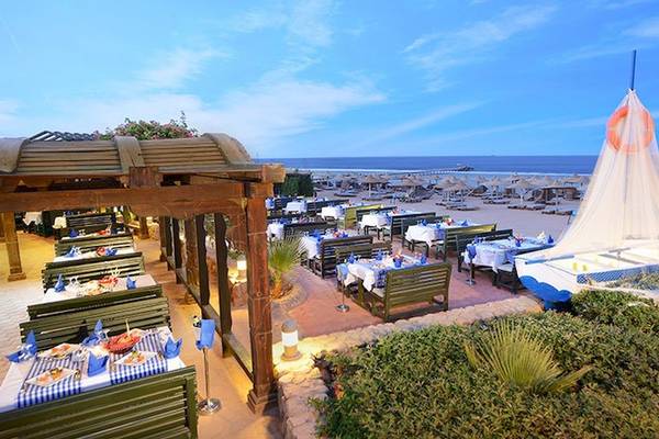 Außenrestaurant des Charmillion Club Resorts am Strand mit Tischen und Sonnenschirmen.