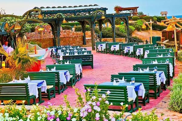 Restaurantbereich des Charmillion Club Resorts mit grünen Bänken und Tischen im Freien.