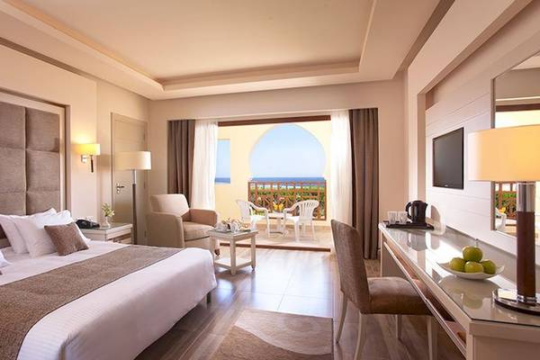 Charmillion Club Resort Hotelzimmer mit Blick auf den Ozean, komfortables Bett, Esstisch, Stühle und Fernseher.