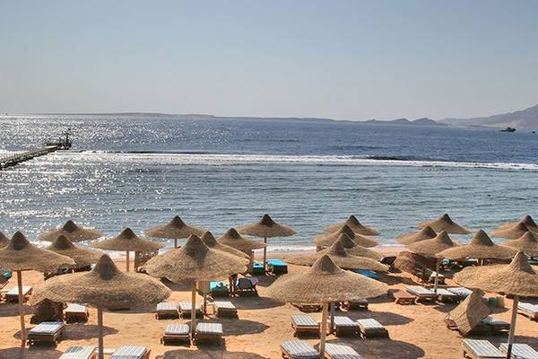 Charmillion Club Resort Strand mit Sonnenhutten und Pieren am Horizont