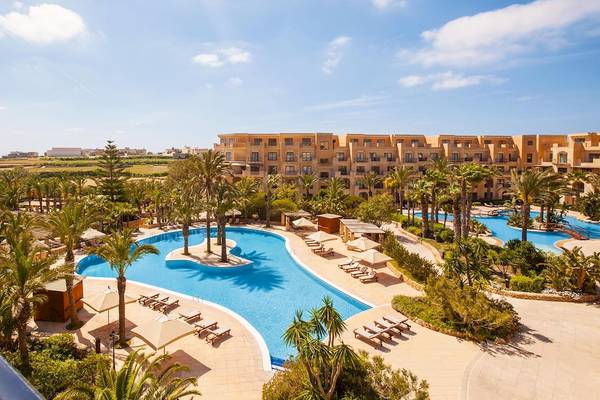 Empfangsbereich des Kempinski Hotels San Lawrenz Malta mit Swimmingpool und Liegestühlen.