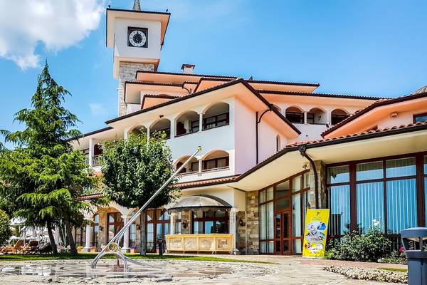 Frontansicht des Helena Sands Hotels mit Turmuhr und bunten Blumen im Vordergrund