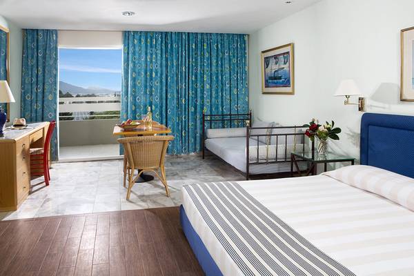 Innenansicht eines Zimmers im Dionysos Hotel mit Bett, Schlafsofa und Balkon.