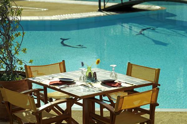 Gartentisch am Pool des Dionysos Hotels mit Blick auf das Wasser.