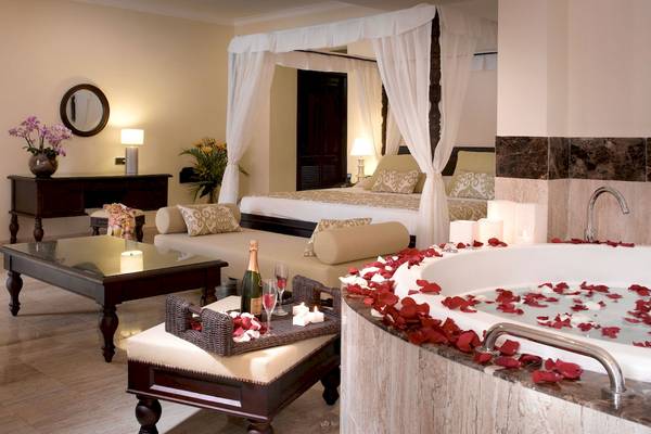 Luxuriöse Suite im TRS Turquesa Hotel mit Badewanne, Bett und Rosenblättern.