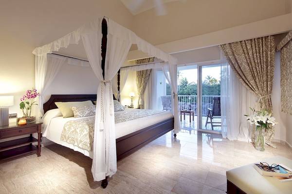 Schlafzimmer im TRS Turquesa Hotel mit Himmelbett, Balkon und Wohnzimmermöbeln.