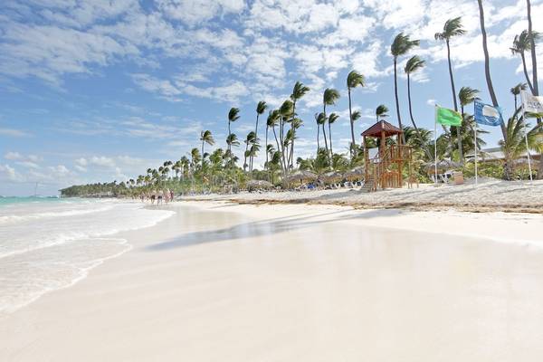 Strand des TRS Turquesa Hotels mit weißen Palmen und Besuchern