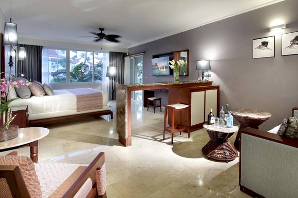 Innenansicht einer Suite im TRS Turquesa Hotel mit Bett, Sitzbereich und Dekoration.