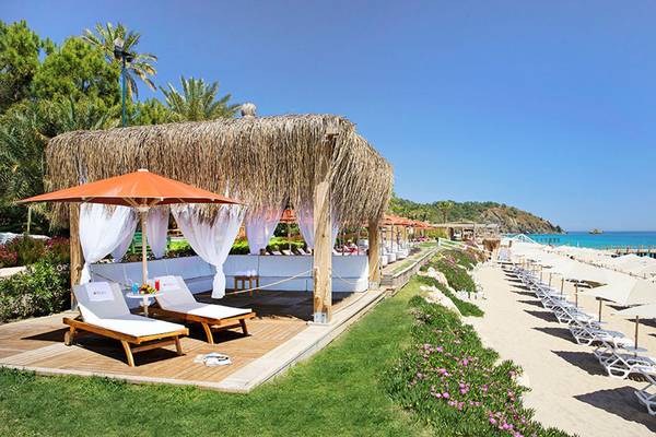 Außenbereich eines Strand-Loungbereichs mit Sonnenschirm und Liegen im Hotel Marti Myra