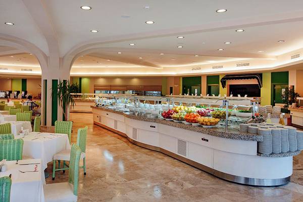 Buffetbereich im Marti Myra Hotel mit vielen Obstschüsseln und grünen Stühlen.