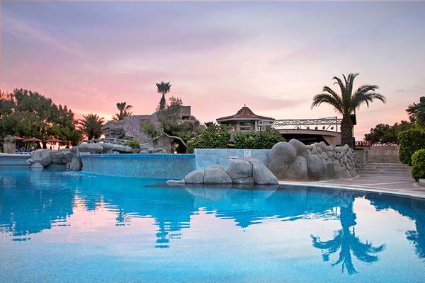 Ein Swimmingpool im Marti Myra Hotel bei Sonnenuntergang mit blauem Wasser und einer felsigen Landschaft.