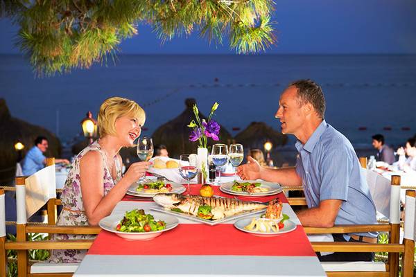 Paar genießt ein Abendessen im Garten des Hotels Marti Myra mit Blick auf das Meer.