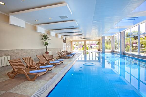 Innenpool des Titan Select Hotels mit Liegestühlen und einer Pflanze.