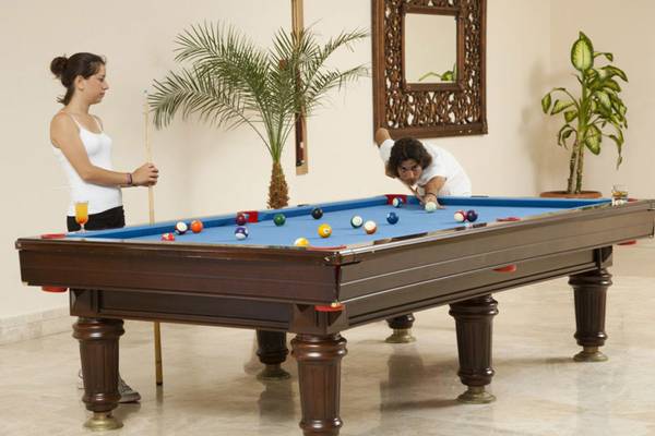 Zwei Personen spielen Billard auf einem großen Tisch im Hotel Titan Select.