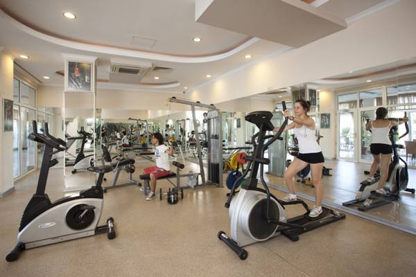 Fitnessraum im Titan Select Hotel mit verschiedenen Trainingsgeräten und Spiegeln.