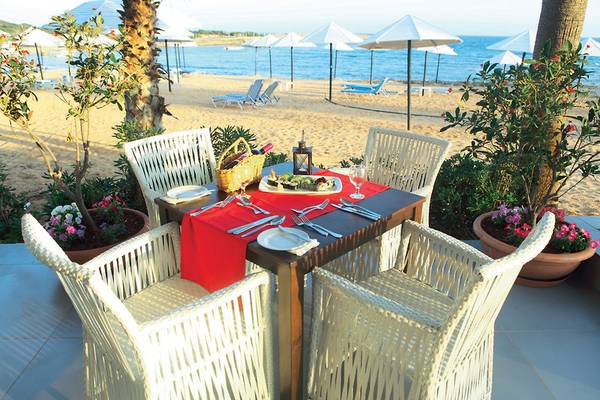 Ein Tisch am Strand des Dome Beach Hotel & Resort, gedeckt mit Speisen und Weingläsern.