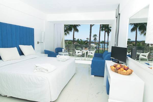 Suite-Zimmer mit Meerblick im Dome Beach Hotel & Resort mit weißem Bett und blauem Kopfteil, Balkon mit Meersicht.