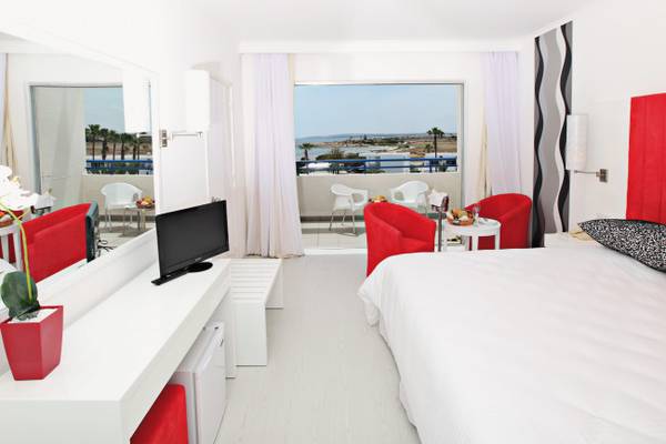 Innenansicht eines Zimmers im Dome Beach Hotel & Resort mit Blick auf den Balkon und das Meer.