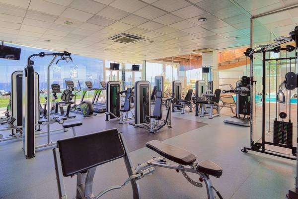 Fitnesscenter im H10 Rubicon Palace Hotel mit modernen Trainingsgeräten und einem Ausblick auf das Schwimmbad.