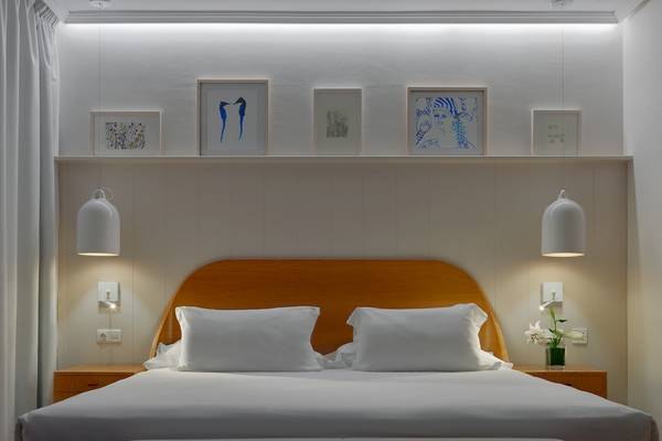Schlafzimmer im H10 Rubicon Palace Hotel mit weißem Bett, Kissen, Nachttischen und Kunstwerken an der Wand.